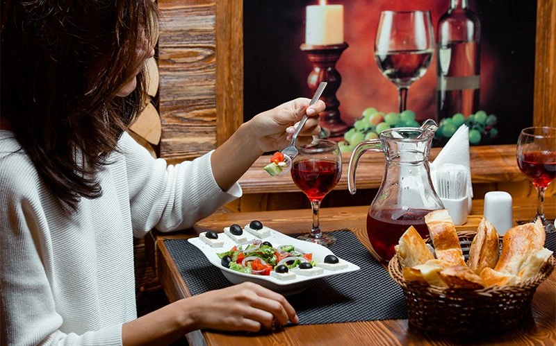 solo-female-diner-enjoying-a-fresh-greek-salad-with-wine