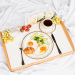 Breakfast in bed with eggs, croissant, fruit and coffee