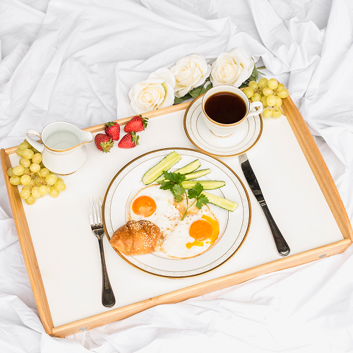 Breakfast in bed with eggs, croissant, fruit and coffee